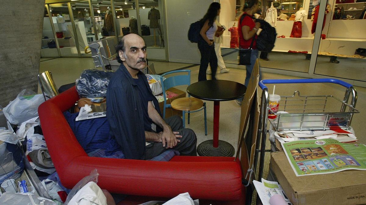 Mehran Karimi Nasseri sentado entre sus pertenencias en la Terminal 1 del aeropuerto Roissy Charles De Gaulle, en París el 11 de agosto de 2004. (AP Foto/Michel Euler, Archivo)