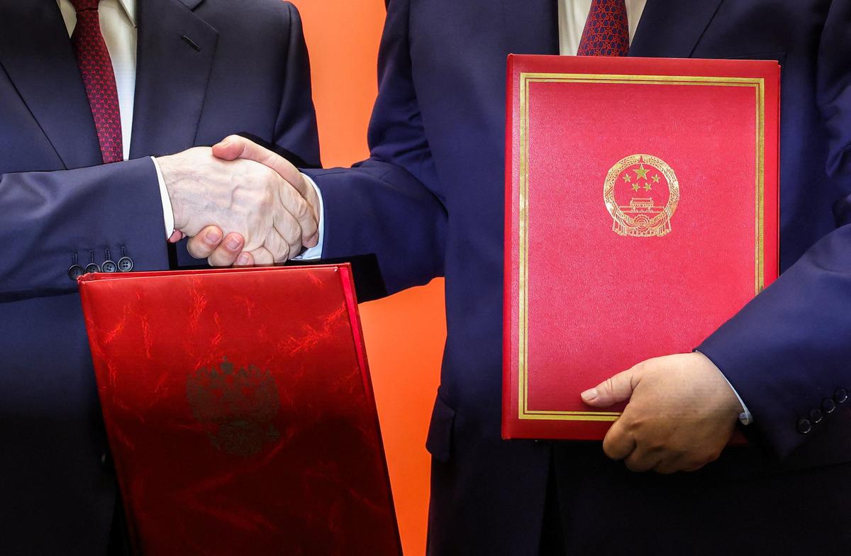 Russian President Vladimir Putin and Chinese President Xi Jinping shake hands as they hold agreement folders during a signing ceremony at the Great Hall of the People in Beijing, China May 20, 2026. REUTERS/Maxim Shemetov/Pool