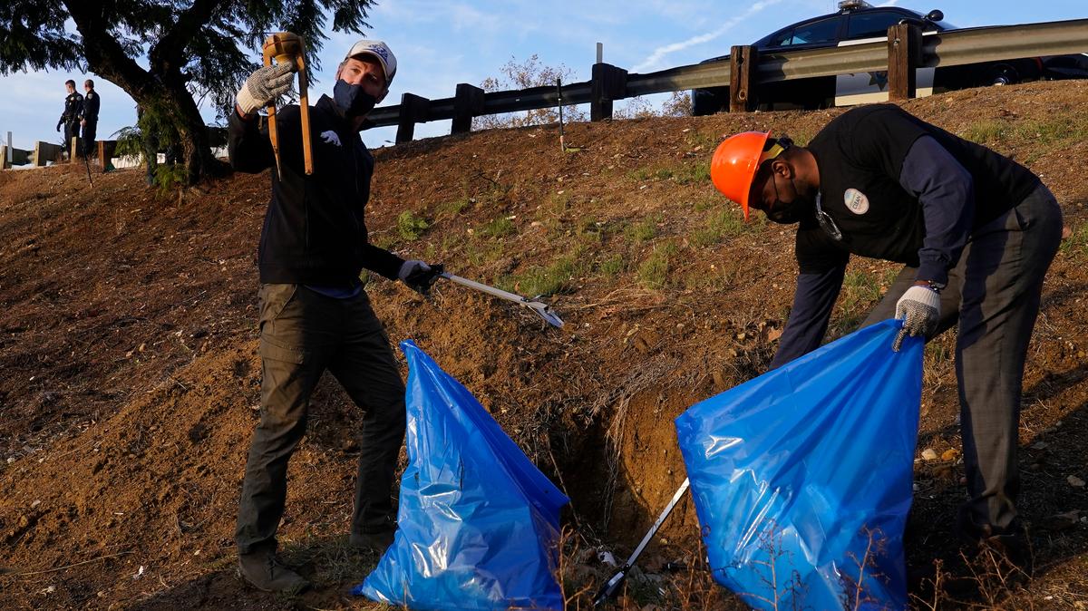 California Gov. Gavin Newsom, left, and Caltrans director Adetokunbo “Toks” Omishakin, right, pick up trash along the 110 freeway in Los Angeles in December.