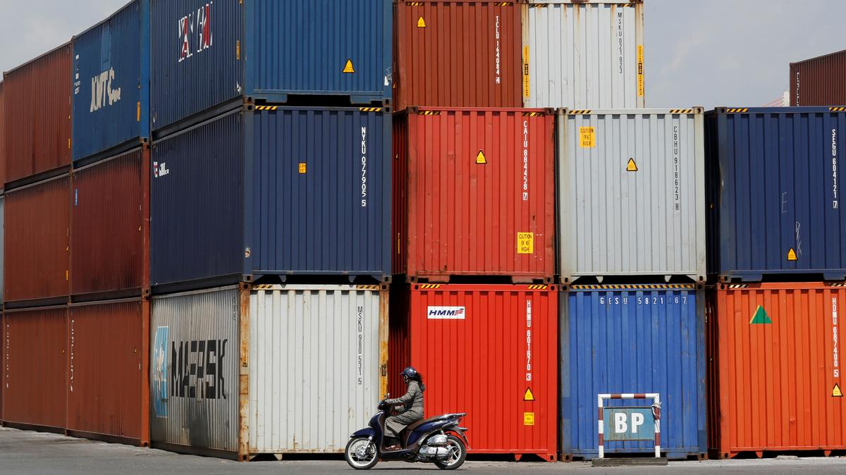 A woman rides a motorcycle as she passes containers at Hai Phong port, Vietnam September 25, 2018. Picture taken September 25, 2018. REUTERS/Kham