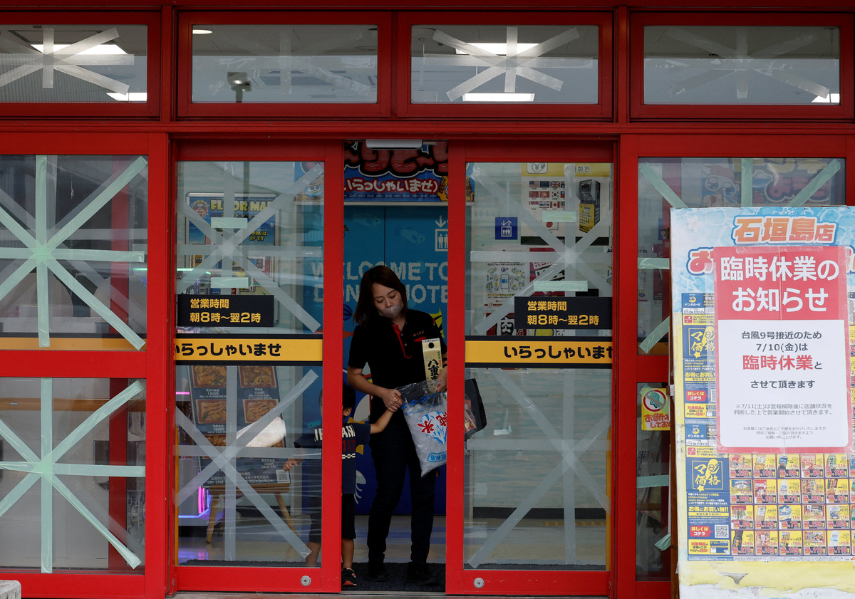 A woman walks out of a shop with duct-taped windows to prevent damage from Typhoon Bavi as it approaches, in Ishigaki, Japan, July 9, 2026. REUTERS/Kim Kyung-Hoon