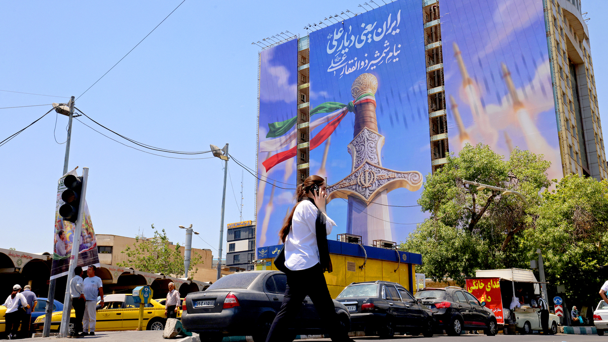 A woman walks past a giant banner depicting Iranian missiles and a sword belonging to Imam Ali, the first Imam of the Shiites, at the Vanak Square in Tehran on June 10, 2026. Iran's foreign ministry said on June 10 that the United States had damaged the ongoing international diplomatic effort to end the war, after more US strikes on targets in southern Iran. (Atta Kenare/AFP/Getty Images/TNS)