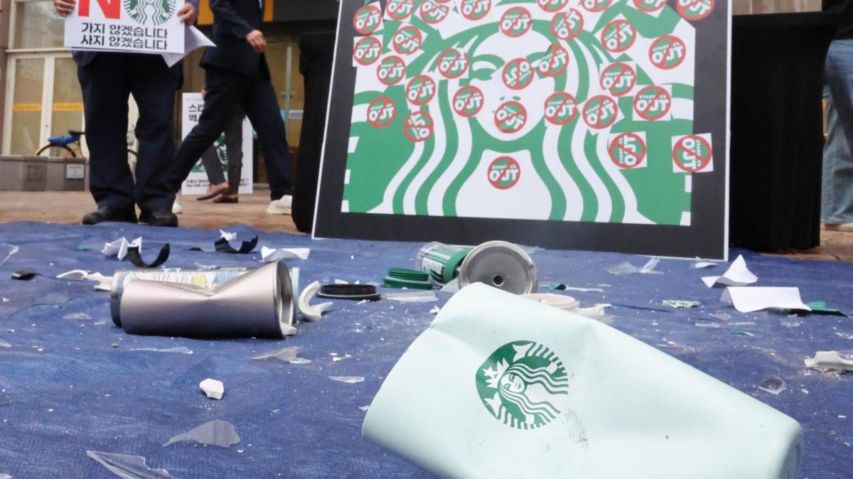 Starbucks tumblers and cups lay on the ground during a rally criticizing Starbucks Korea's "Tank Day" promotional event outside a store in Gwangju on Thursday. Photo by Yonhap