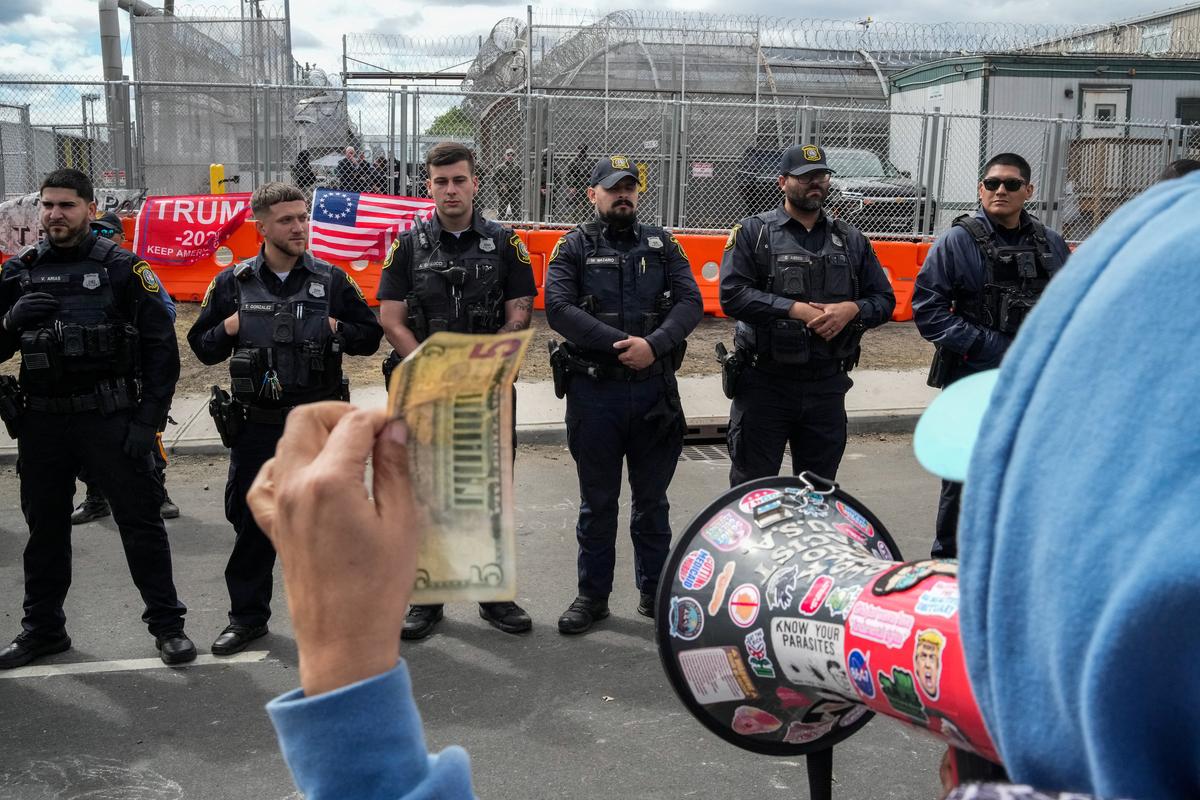 A protester using a megaphone shows a five-dollar bill to Newark police officers outside the Delaney Hall detention centre in Newark, New Jersey, U.S., May 30, 2026. REUTERS/Eduardo Munoz