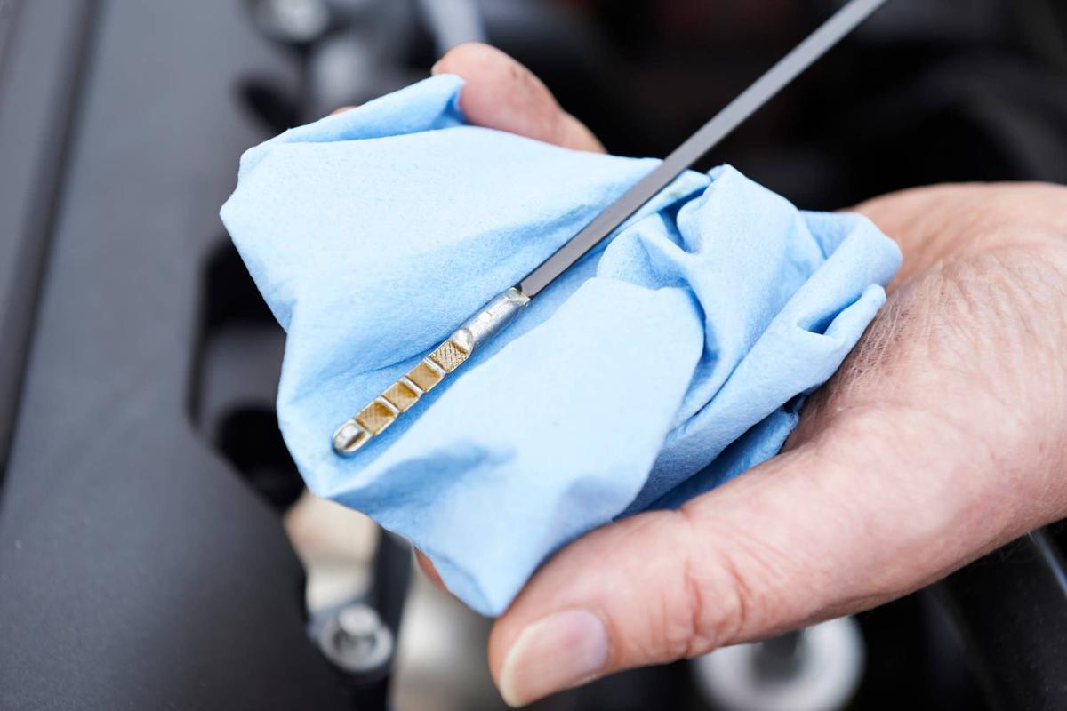 Close-Up Of Man Checking Car Engine Oil Level On Dipstick