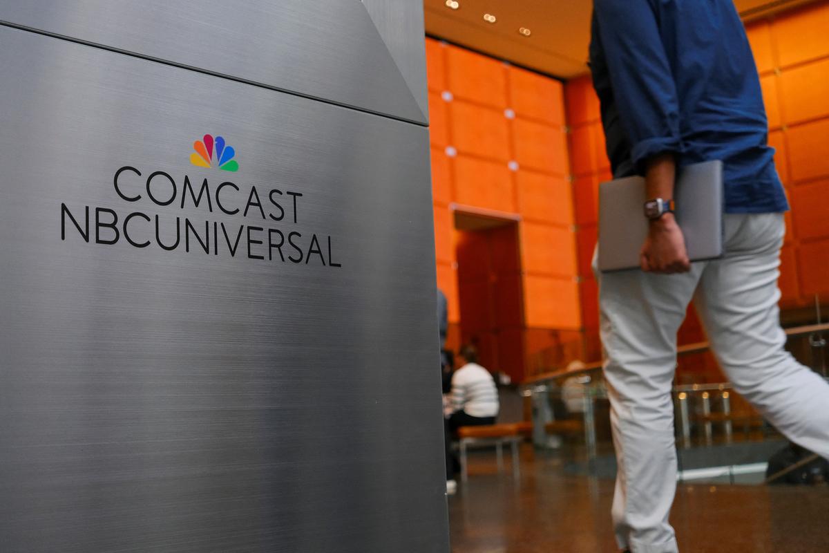 A person walks past a signage of Comcast and NBC Universal in the lobby of the corporate headquarters of Comcast, which announced plans to spin-off the bulk of its fading NBCUniversal cable TV networks, including MSNBC and CNBC, in Philadelphia, Pennsylvania, U.S. November 20, 2024. REUTERS/Bastiaan Slabbers