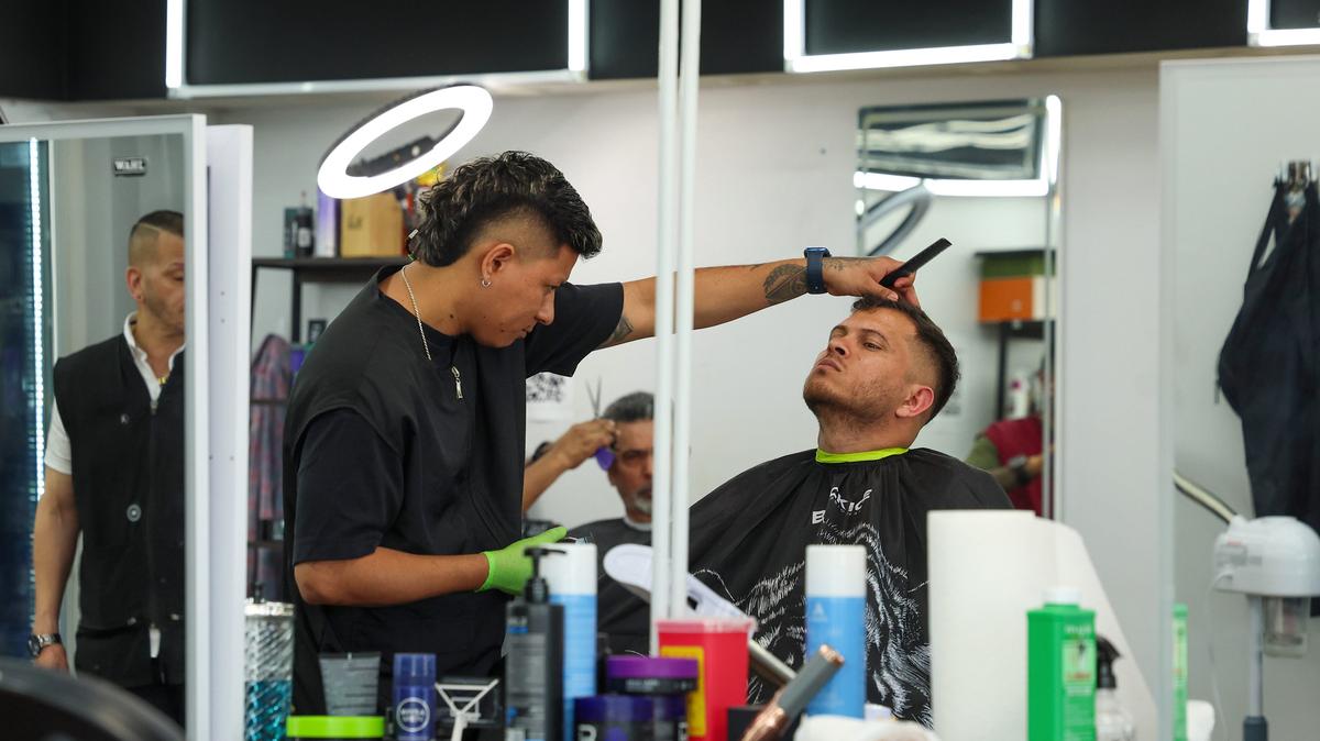 Barber Anderson Garcia, center left, works on a mid-fade hairstyle for client Albert Morales, right, at Epic Studio Barber & Stylists in Chicago on May 15, 2026. (Stacey Wescott/Chicago Tribune/TNS)