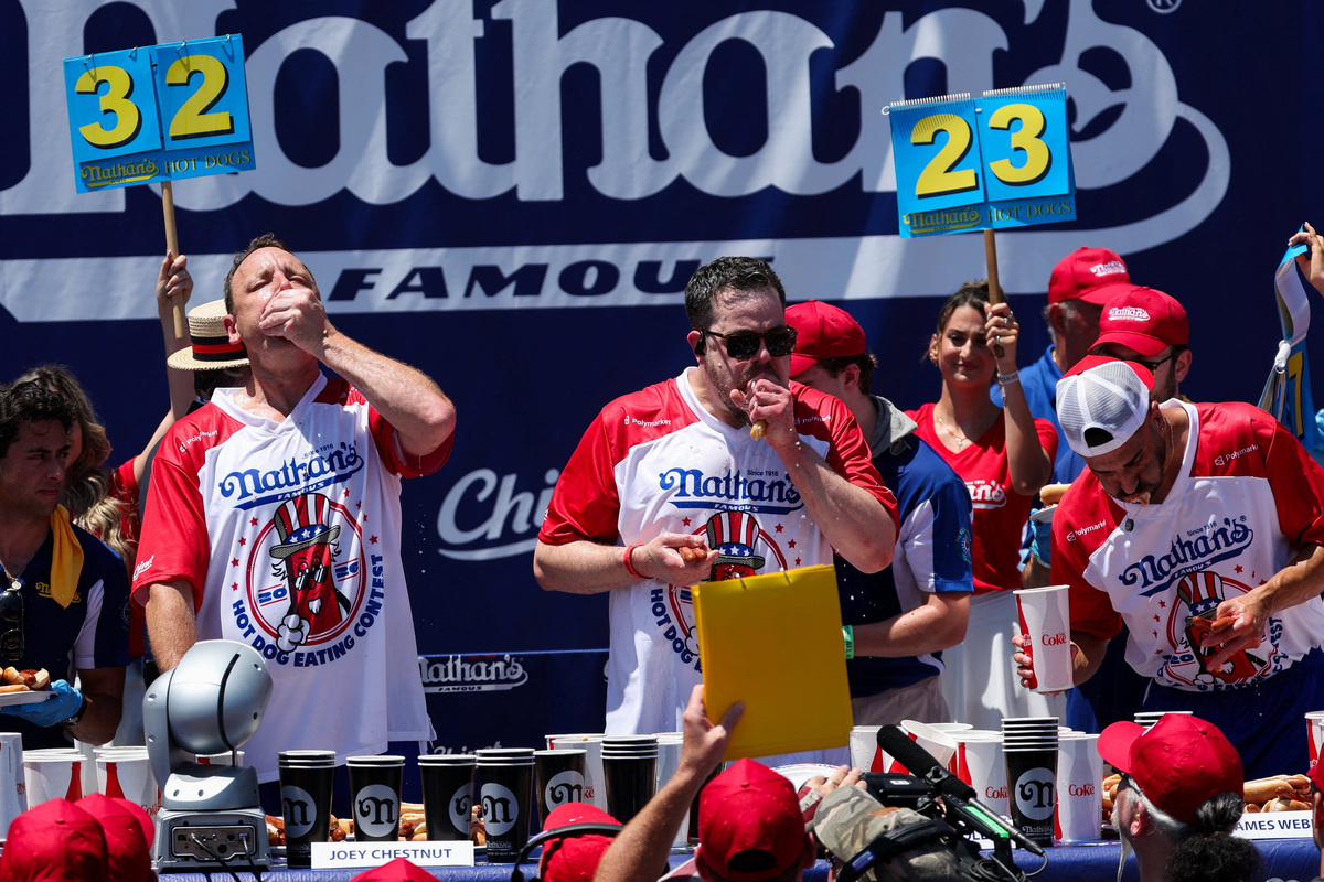 Joey Chestnut, Patrick Bertoletti from Chicago, Illinois, and James Webb from Sydney, Australia, participate in the 2026 Nathan's Famous International Hot Dog Eating Contest, at Coney Island, Brooklyn in New York City, U.S., July 4, 2026. REUTERS/Jordan Tovin