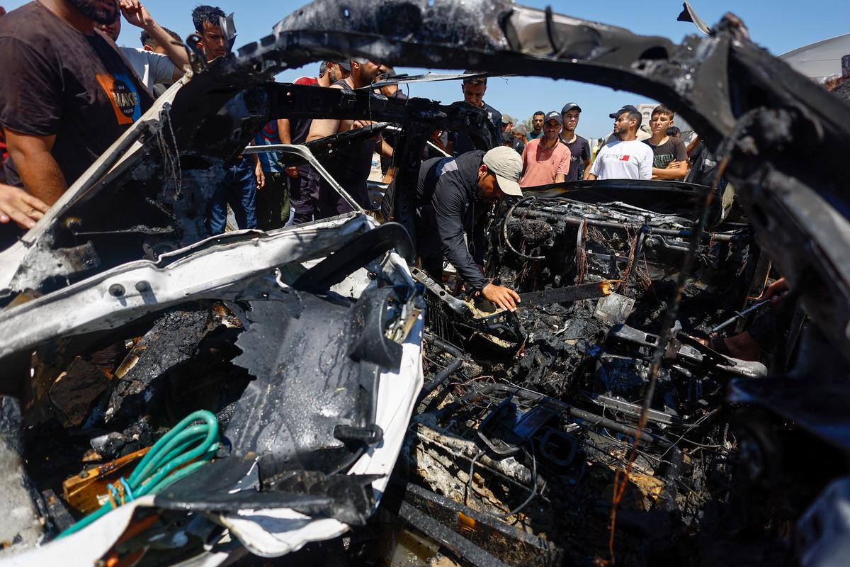 Palestinians inspect a destroyed vehicle at the site of an Israeli strike, in Deir al-Balah, in the central Gaza Strip June 2, 2026. REUTERS/Mahmoud Issa