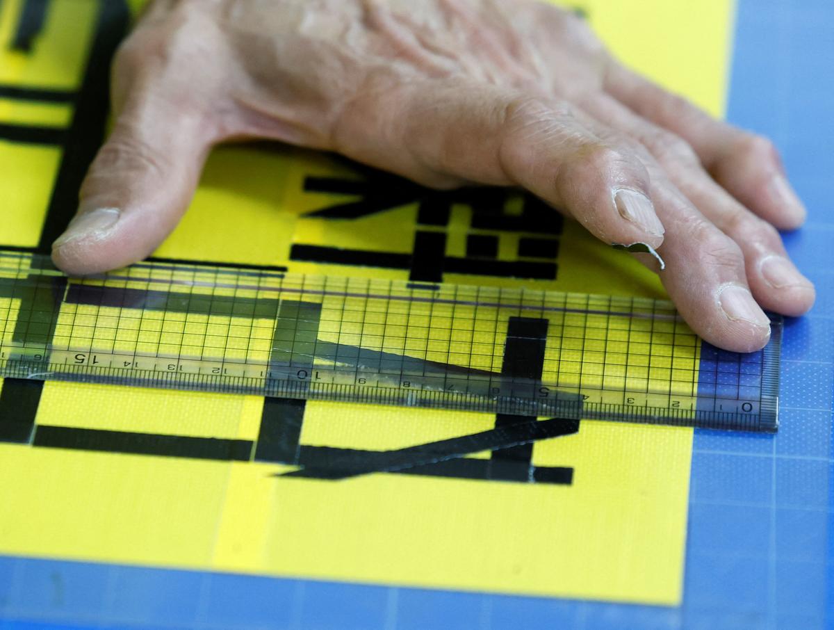 Shuetsu Sato, a security guard whose handmade duct-tape signs have gained widespread recognition, makes a duct-tape sign at a security company office where he works, in Tokyo, Japan, May 1, 2026.   REUTERS/Kim Kyung-Hoon