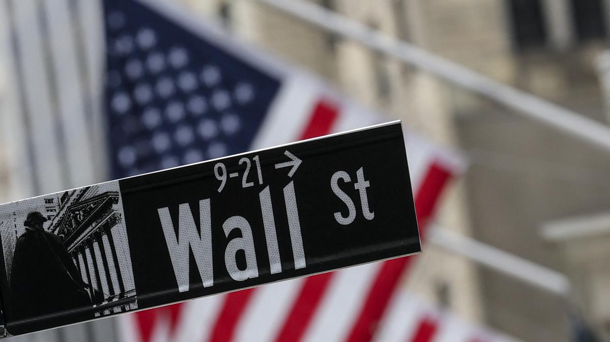 The American flag flies behind a Wall Street sign near the New York Stock Exchange (NYSE) in New York City on April 22, 2026.