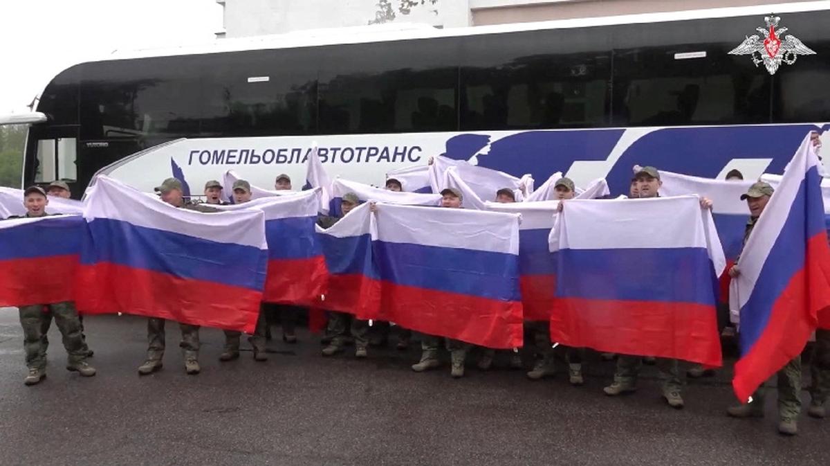 A still image from a video released by the Russian Defence Ministry shows what it said to be Russian service personnel captured by Ukrainian forces and released during the latest exchange of prisoners of war in the course of Russia-Ukraine conflict, as they pose for a picture with flags in front of a bus at an unknown location in Belarus, in this image taken from handout footage released on May 15, 2026. Russian Defence Ministry/Handout via REUTERS