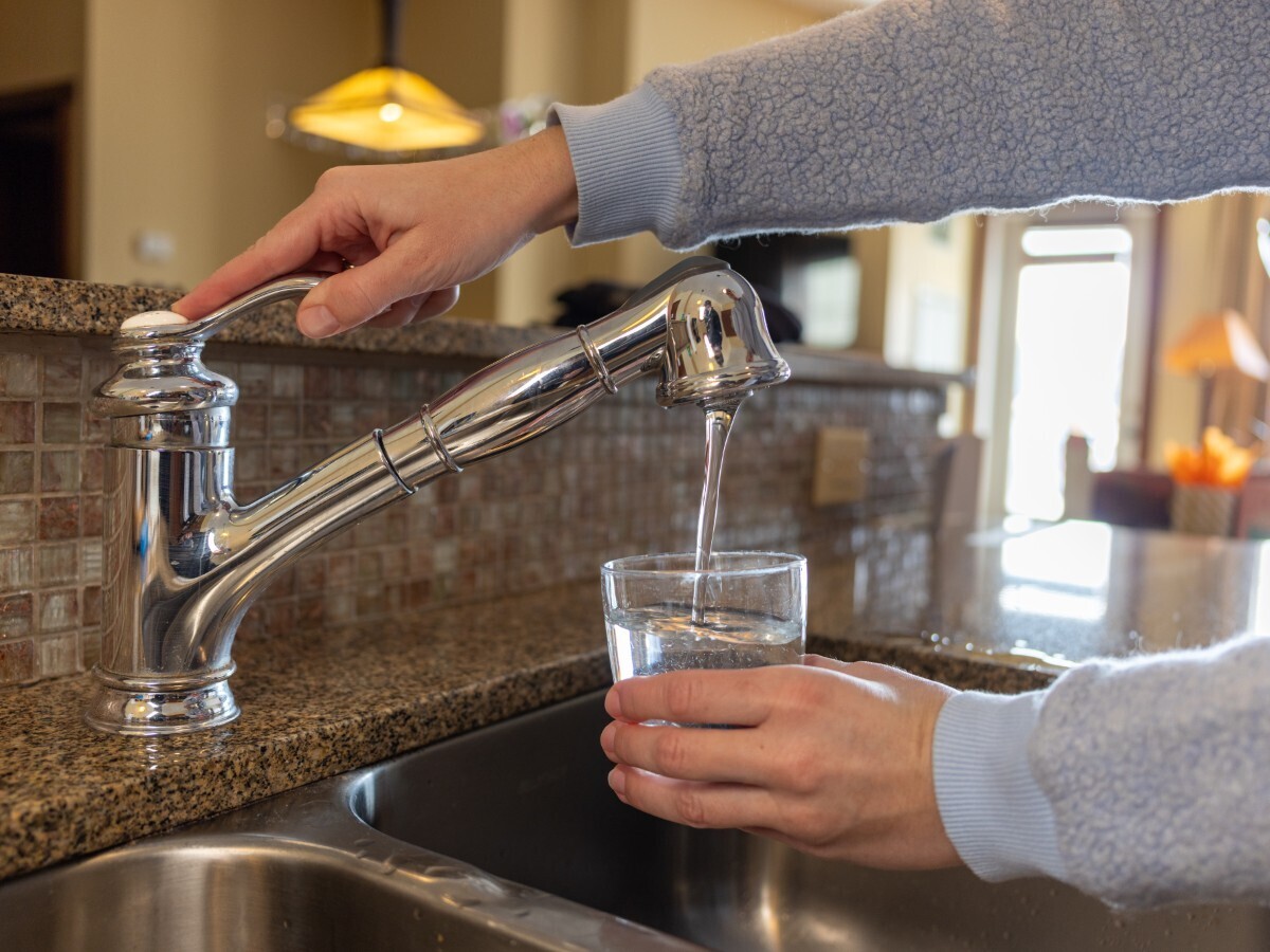  Stock image: a person fills a glass with tap water for drinking in a kitchen. 