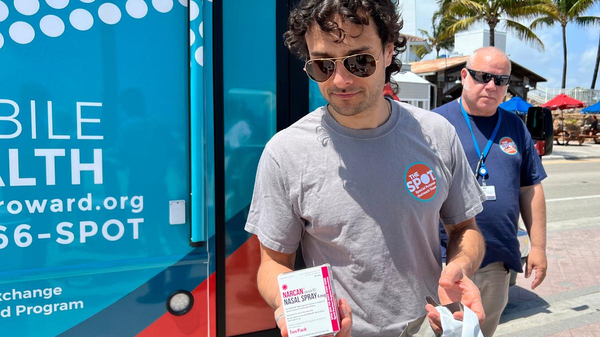 Huston Ochoa, a clinical counselor for The Spot, hands out samples of Narcan, which can reduce opioid overdoses, to spring breakers in Fort Lauderdale on March 31, 2022. 
