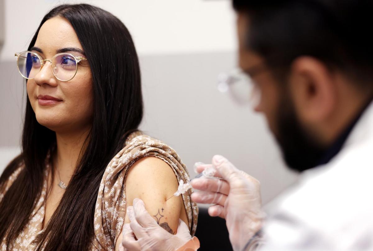 Heidi Salguero, 32, of Bell, left, receives a flu vaccine from pharmacist Deep Patel, right, at CVS in Huntington Park on Aug. 28, 2024. 