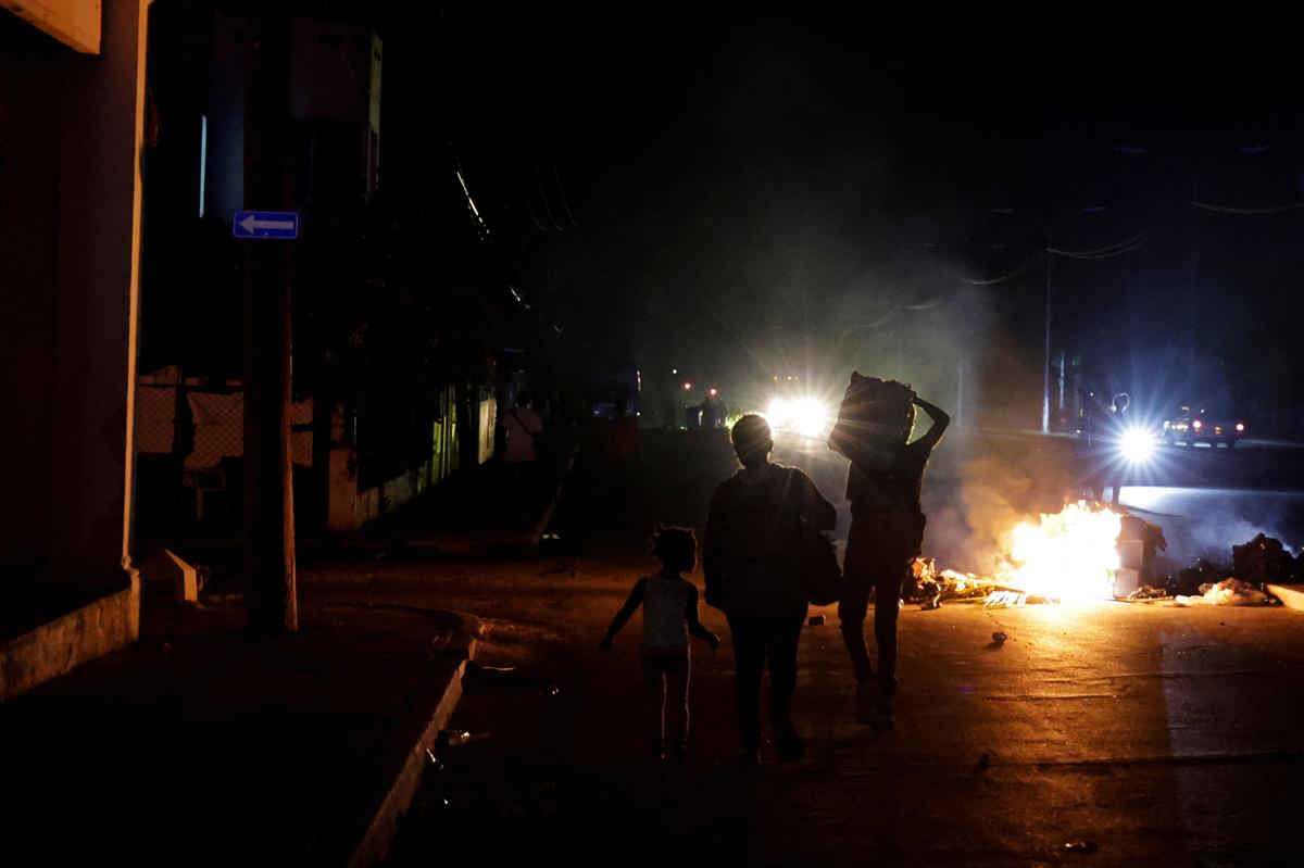 People walk past trash set on fire in the middle of a street during a protest against frequent power cuts as Havana faces its worst rolling blackouts in decades amid a U.S. blockade that has strangled the island of fuel, in Havana, Cuba, May 13, 2026. REUTERS/Norlys Perez