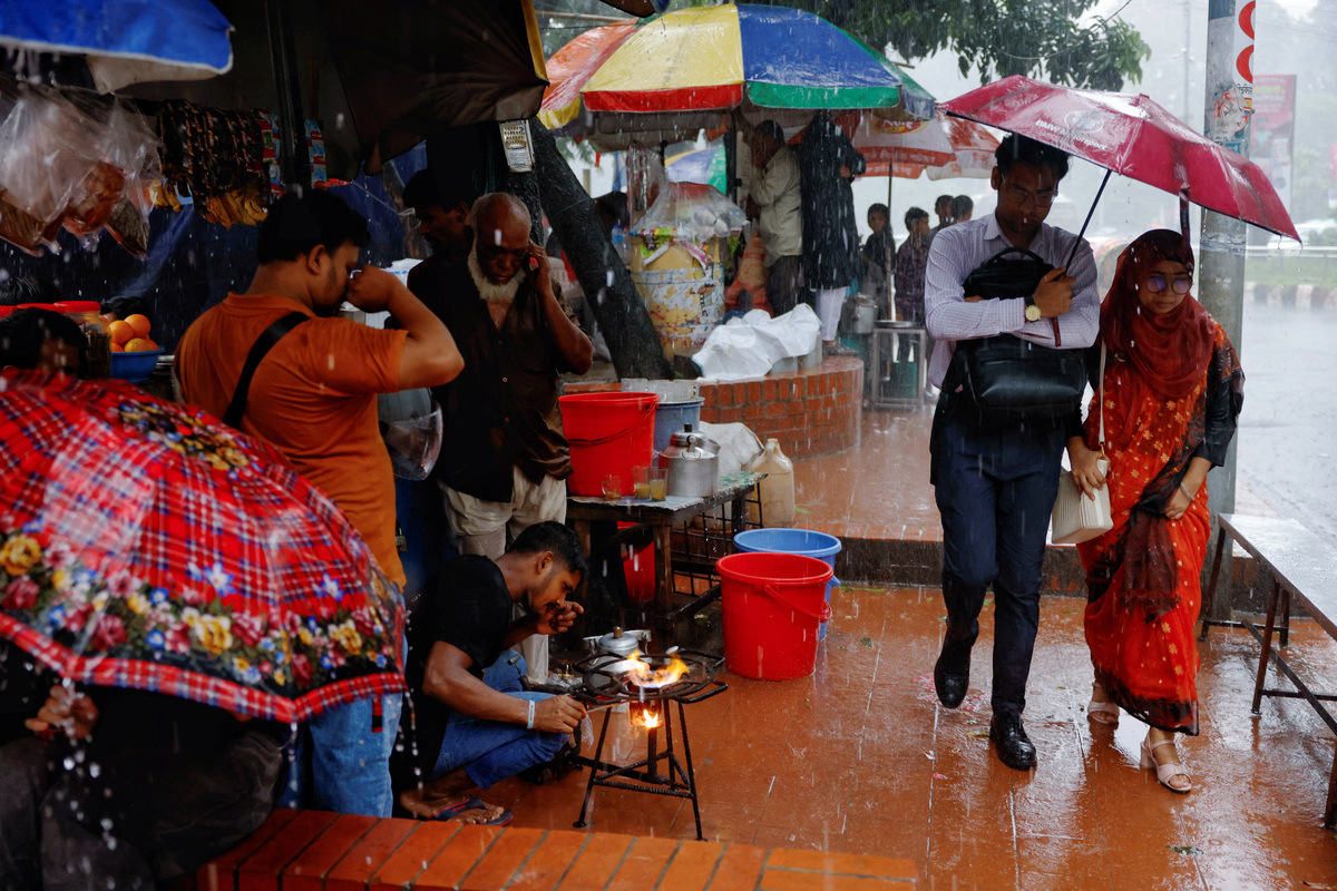 People walk with an umbrella during torrential rain in Dhaka, Bangladesh, July 7, 2026. REUTERS/Mohammad Ponir Hossain
