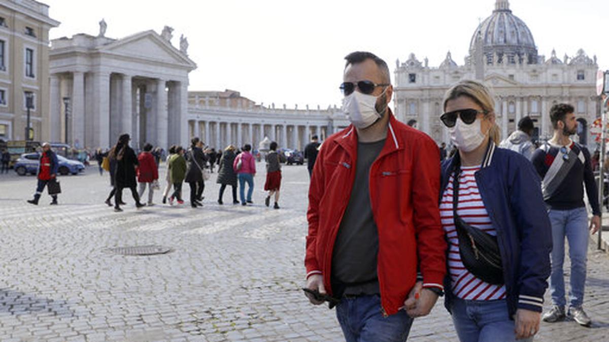 Una pareja usando mascarillas camina por la Plaza de San Pedro, en el Vaticano, el 27 de febrero de 2020, semanas antes de que el estallido de la pandemia del coronavirus afectara dramáticamente el turismo en Italia.