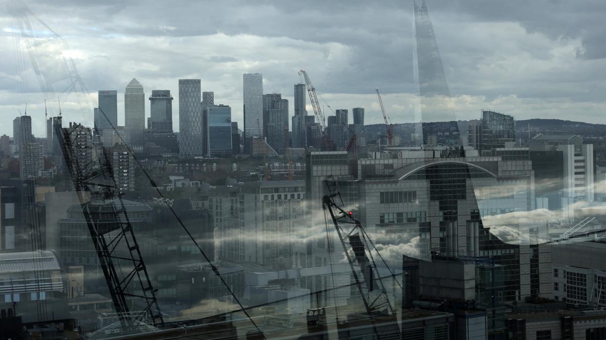 Skyscrapers of the Canary Wharf commercial district are seen with The Shard building and construction cranes reflected in a perimeter glass wall of the viewing area of Garden at 120, in the City of London financial district, in London, Britain, September 23, 2025. REUTERS/Toby Melville