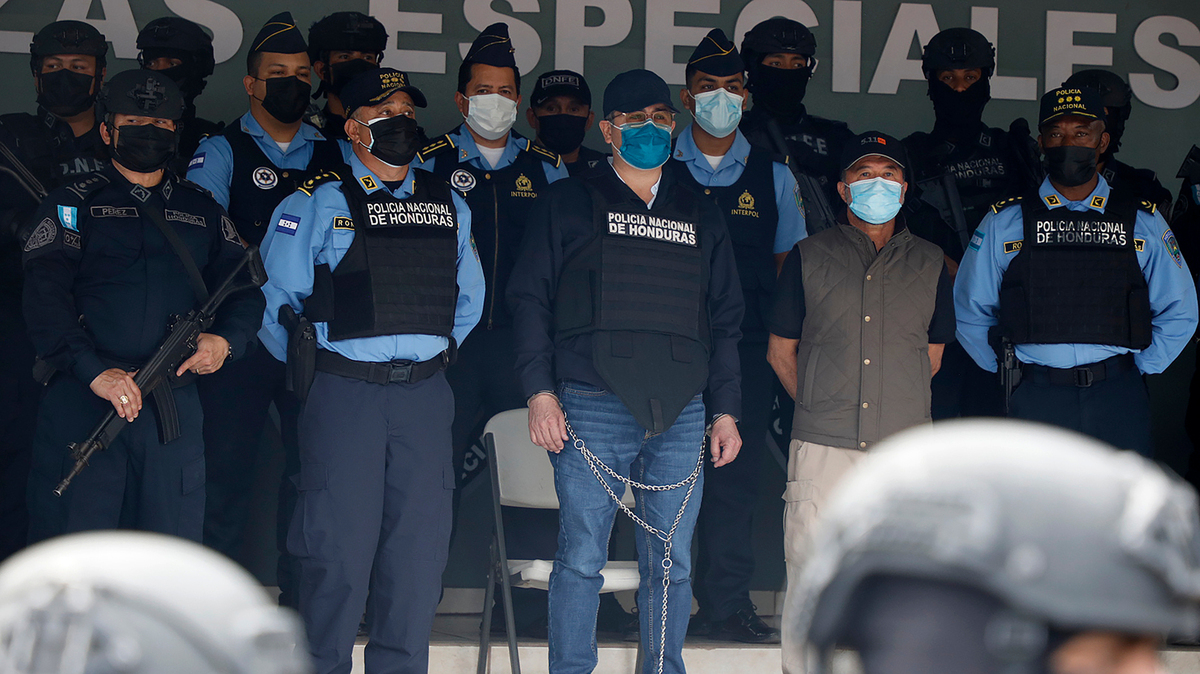 El expresidente hondureño Juan Orlando Hernández (centro) es presentado ante los medios de comunicación en la sede de la Policía Nacional, en Tegucigalpa, el martes 15 de febrero de 2022. (AP Foto/Elmer Martinez)