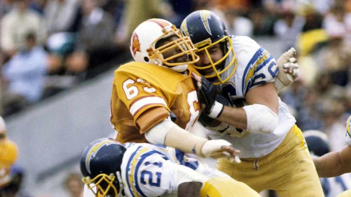  Dec 13, 1981; Tampa, FL, USA; FILE PHOTO; San Diego Chargers running back James Brooks (21) and tackle Billy Shields (66) block Tampa Bay Buccaneers defensive end Lee Roy Selmon (63) at Tampa Stadium. Mandatory Credit: Manny Rubio-Imagn Images | Manny Rubio-Imagn Images 