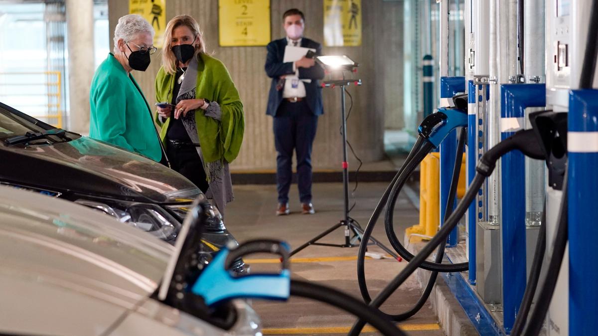 Gina McCarthy (izq.), asesora de políticas climáticas de la Casa Blanca, conversa con Cathy Zoi, directora ejecutiva de EVgo, mientras cargan uno de los autos eléctricos de esta la empresa, el 22 de abril de 2021, en Washington D.C.