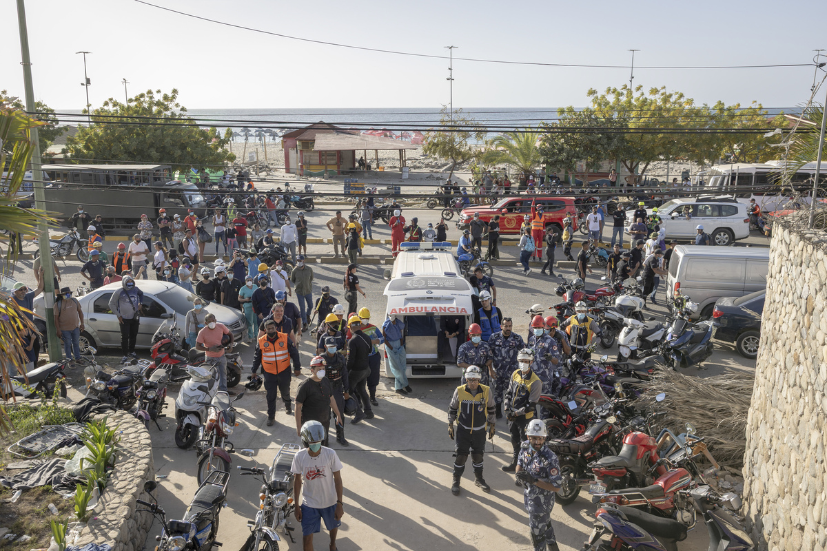 People gather with an ambulance after potential signs of light were heard from inside the Gabarra building that collapsed in last week's earthquakes in La Guaira, Venezuela, on Monday, June 29, 2026. It has been six days since devastating twin earthquakes flattened entire residential neighborhoods in Venezuela, and dozens of new bodies are still being hauled out of the rubble. (Fabiola Ferrero/The New York Times)