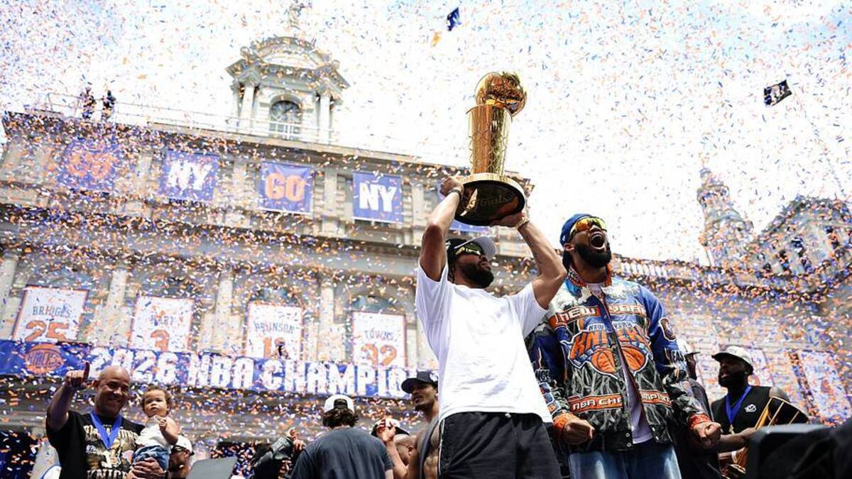  Jalen Brunson and Karl-Anthony Towns celebrate with the Larry O'Brien Trophy during the Knicks' championship ticker tape parade in New York City. | Angelina Katsanis/Getty Images 