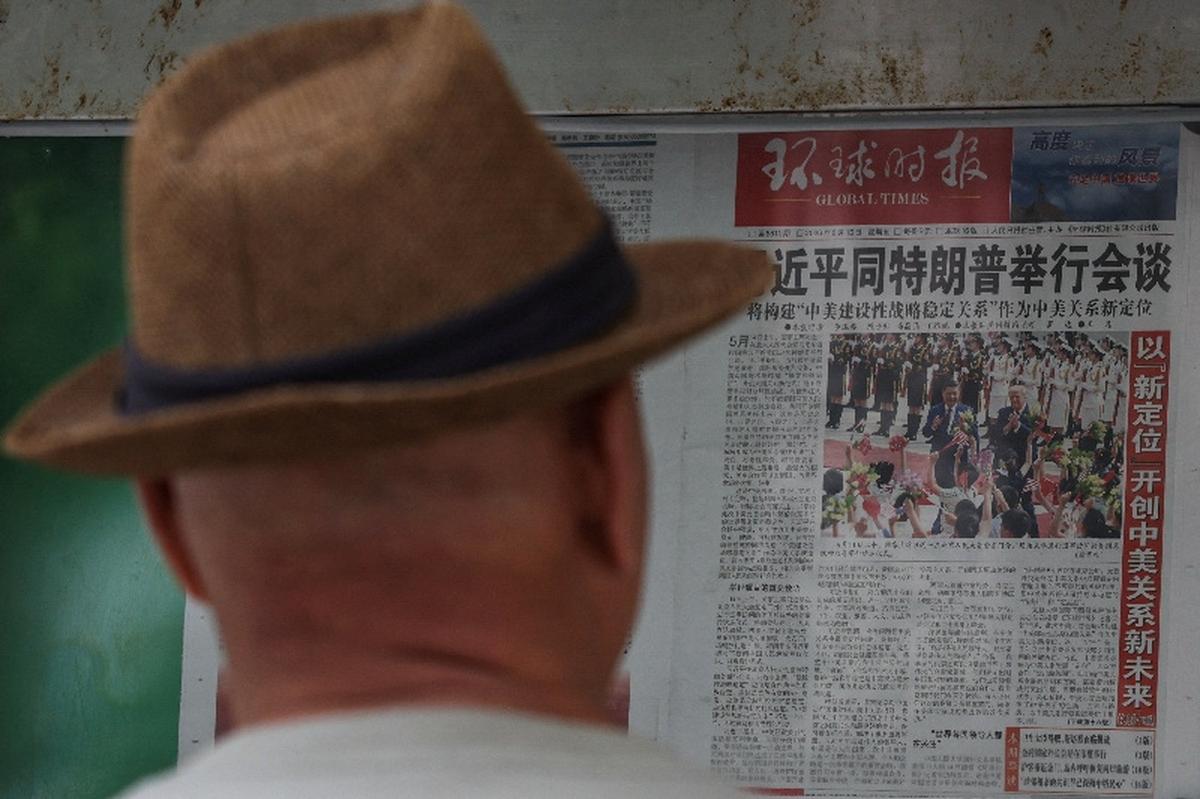 A man reads Global Times newspaper with an image of Chinese President Xi Jinping meeting U.S. President Donald Trump at the Great Hall of the People on the front page, at a billboard in Beijing, China May 15, 2026. REUTERS/Tingshu Wang