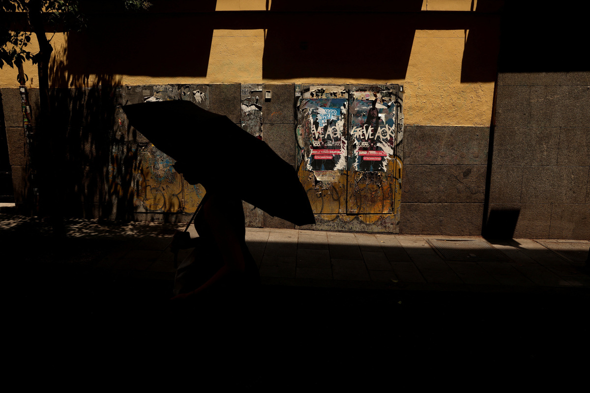 A woman uses an umbrella to shield herself from the sun during a heatwave in Madrid, Spain, July 7, 2026. REUTERS/Susana Vera
