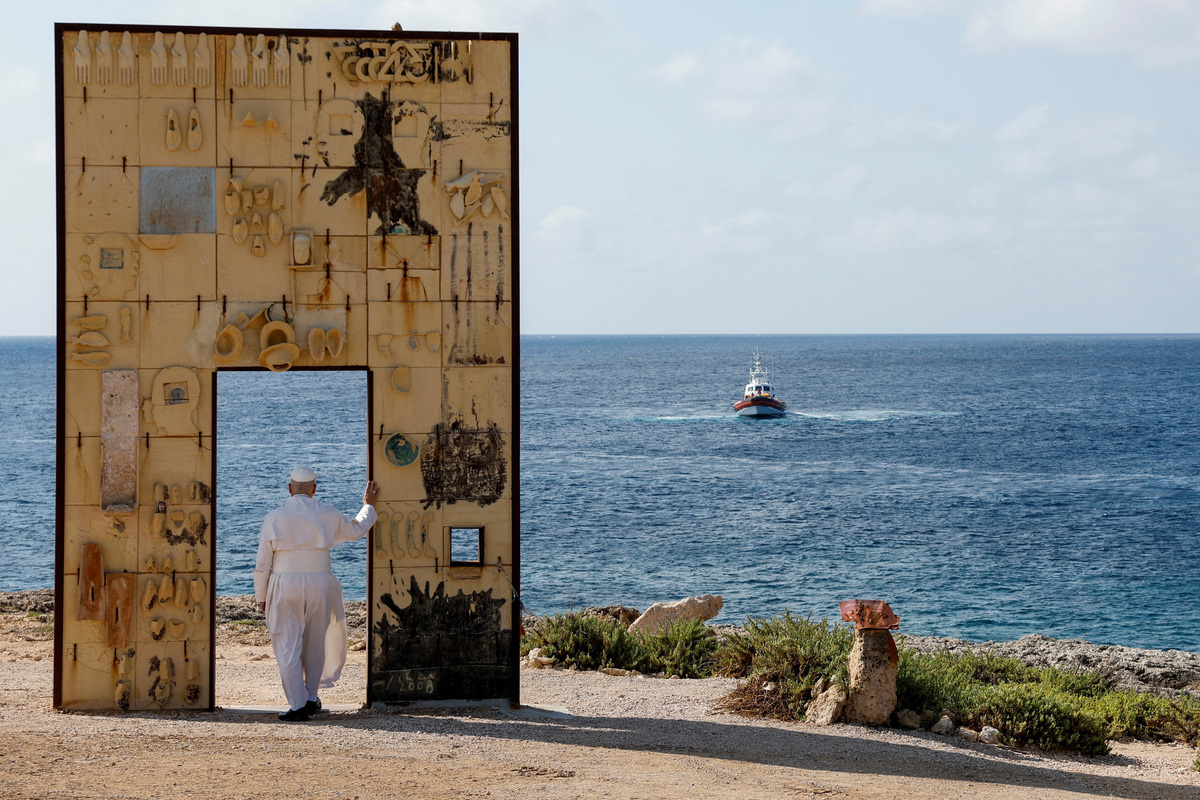 Pope Leo stops at "Porta d’Europa" memorial, with an Italian Coast Guard vessel sailing in the background, as he visits the island of Lampedusa, a key entry point for migrants crossing the Mediterranean Sea, during a pastoral trip, Italy, July 4, 2026. REUTERS/Remo Casilli