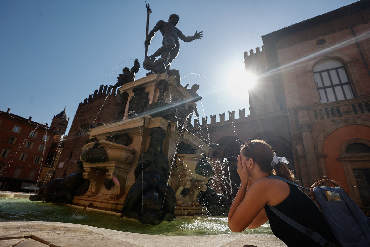 A woman splashes water on her face at the Fountain of Neptune during hot weather in Bologna, Italy, June 20, 2026. REUTERS/Vincenzo Livieri