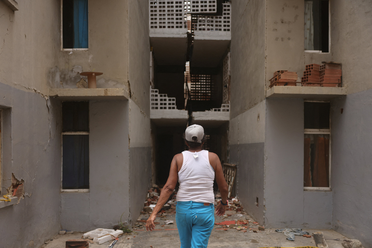 Maru Nunez, 59, walks to her apartment in a damaged housing building at Mision Vivienda, which was affected by the June 24 earthquakes, in Catia La Mar, La Guaira State, Venezuela, July 12, 2026. REUTERS/Leonardo Fernandez Viloria