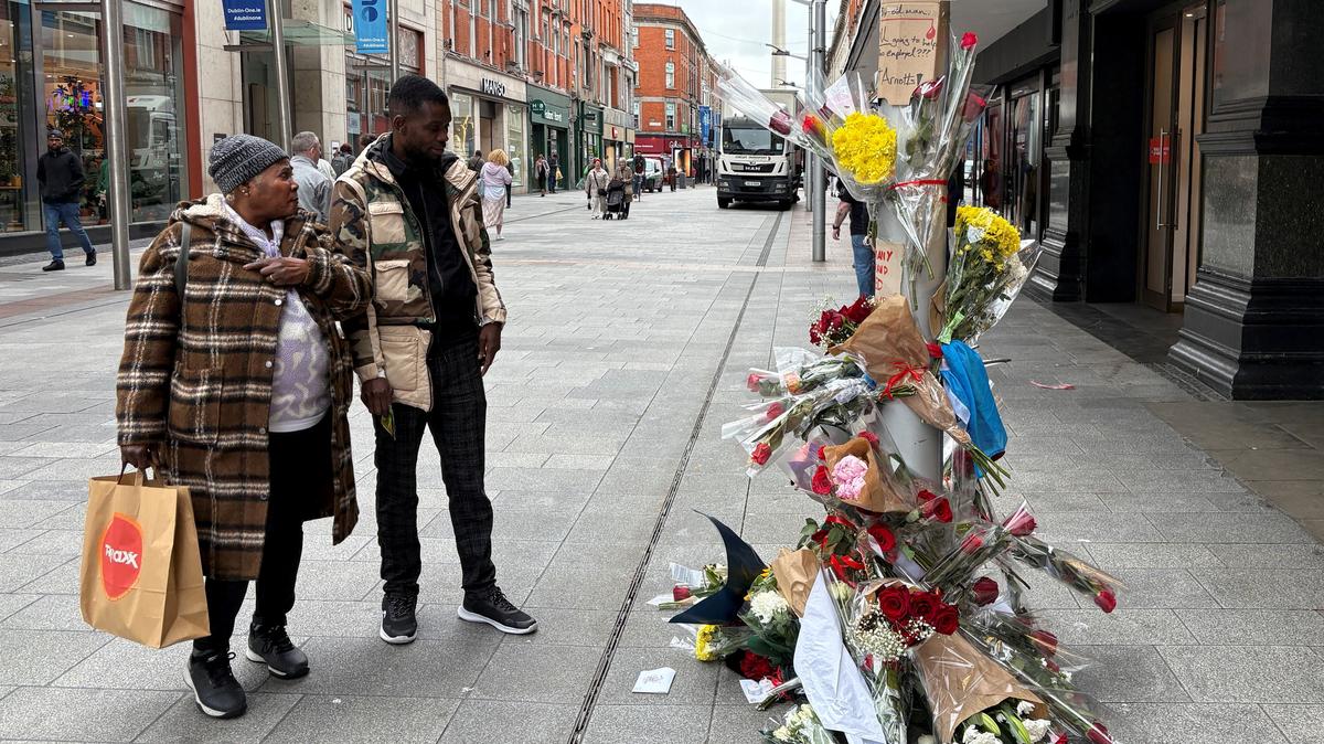 People stand near flowers laid outside a department store on Henry Street where a Congolese-born man, Yves Sakila, was restrained by security guards last week and later pronounced dead in hospital, in Dublin, Ireland, May 20, 2026. REUTERS/Conor Humphries