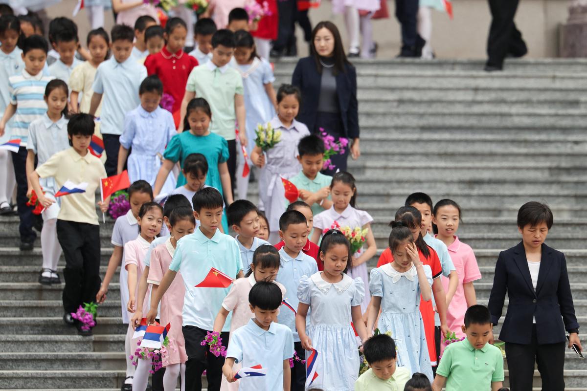 Children holding Russian and Chinese flags walk ahead of a welcoming ceremony for Russian President Vladimir Putin at the Great Hall of the People in Beijing, China May 20, 2026. REUTERS/Maxim Shemetov/Pool