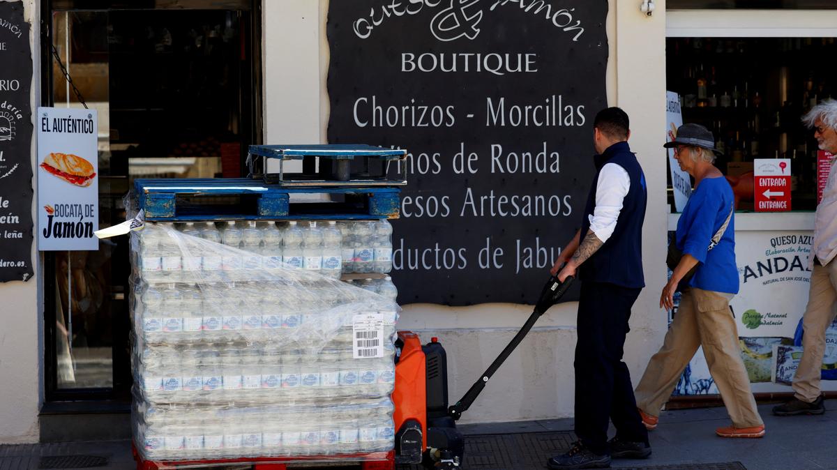 A worker of a supermarket pushes a shopping cart with bottles of water in Ronda, Spain, May 21, 2026. REUTERS/Jon Nazca