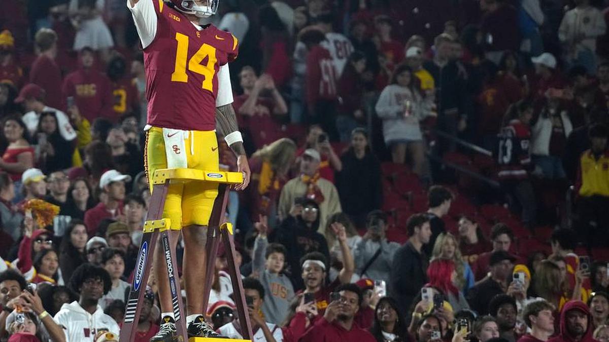  Nov 29, 2025; Los Angeles, California, USA; Southern California Trojans quarterback Jayden Maiava (14) leads the Spirit of Troy marching band in a rendition of Tribute to Troy after the game against the UCLA Bruins at United Airlines Field at Los Angeles Memorial Coliseum. Mandatory Credit: Kirby Lee-Imagn Images | Kirby Lee-Imagn Images 