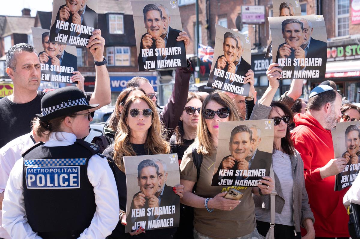 Protesters hold up placards against British Prime Minister Keir Starmer during his visit to Golders Green, north west London, following a terror attack on Wednesday morning in which two men were stabbed, in London, Britain, April 30, 2026.    Stefan Rousseau/Pool via REUTERS