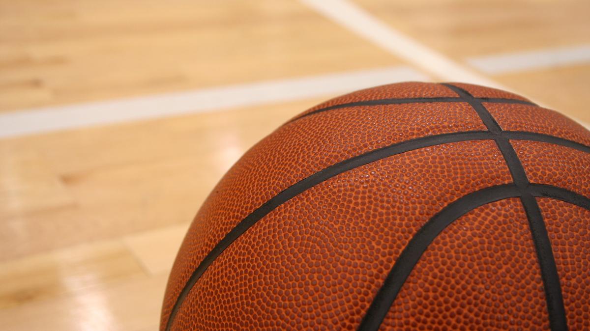 A basketball rests on a hardwood court.