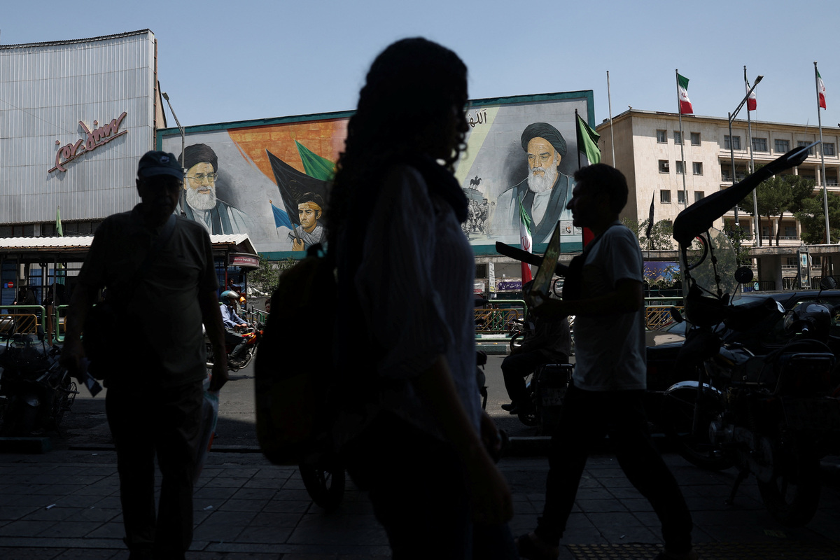People walk past a mural depicting the late leader of the Islamic Revolution, Ayatollah Ruhollah Khomeini, and the late Iran's Supreme Leader Ayatollah Ali Khamenei, on a street in Tehran, Iran, June 9, 2026. Majid Asgaripour/WANA (West Asia News Agency) via REUTERS