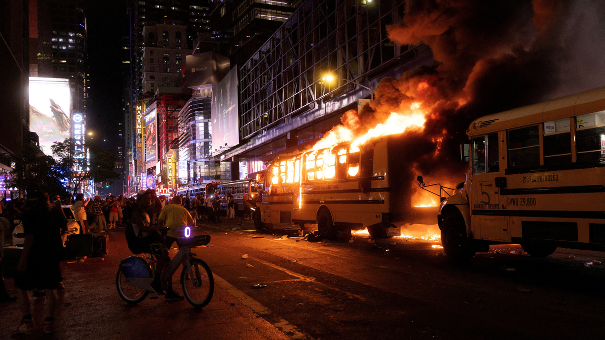 Revellers and fans celebrating the New York Knicks' win over the San Antonio Spurs and World Cup festivities watch as a city shuttle bus catches fire outside the Port Authority Bus Terminal in New York, U.S., June 14, 2026. The shuttles had been brought in to transport spectators to and from the New York/New Jersey stadium for the 2026 FIFA World Cup. REUTERS/Ed Ou