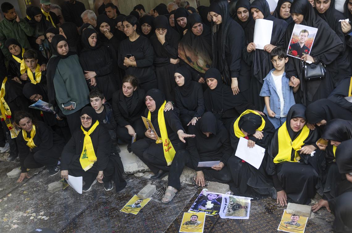 Mourners, some wearing yellow Hezbollah scarves, during a mass funeral for 20 people in the southern Lebanese village of Qlaileh, on Tuesday, April 21, 2026. The cease fire has given families who had fled because of Israeli evacuation warnings the opportunity to return to the village and bury their relatives killed during the war after being temporarily buried in transit cemeteries. (David Guttenfelder/The New York Times)