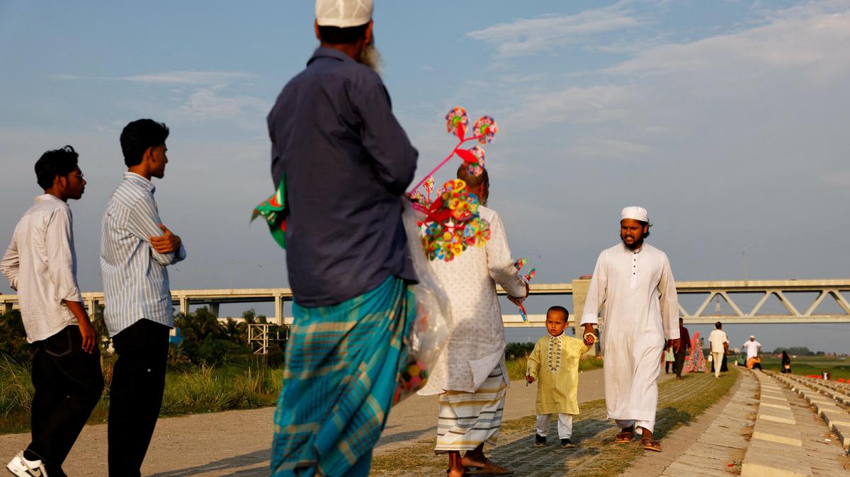 A man with a child approaches a vendor to purchase a pinwheel toy, on the bank of Padma River, in Munshiganj, Bangladesh, May 4, 2026. REUTERS/Mohammad Ponir Hossain