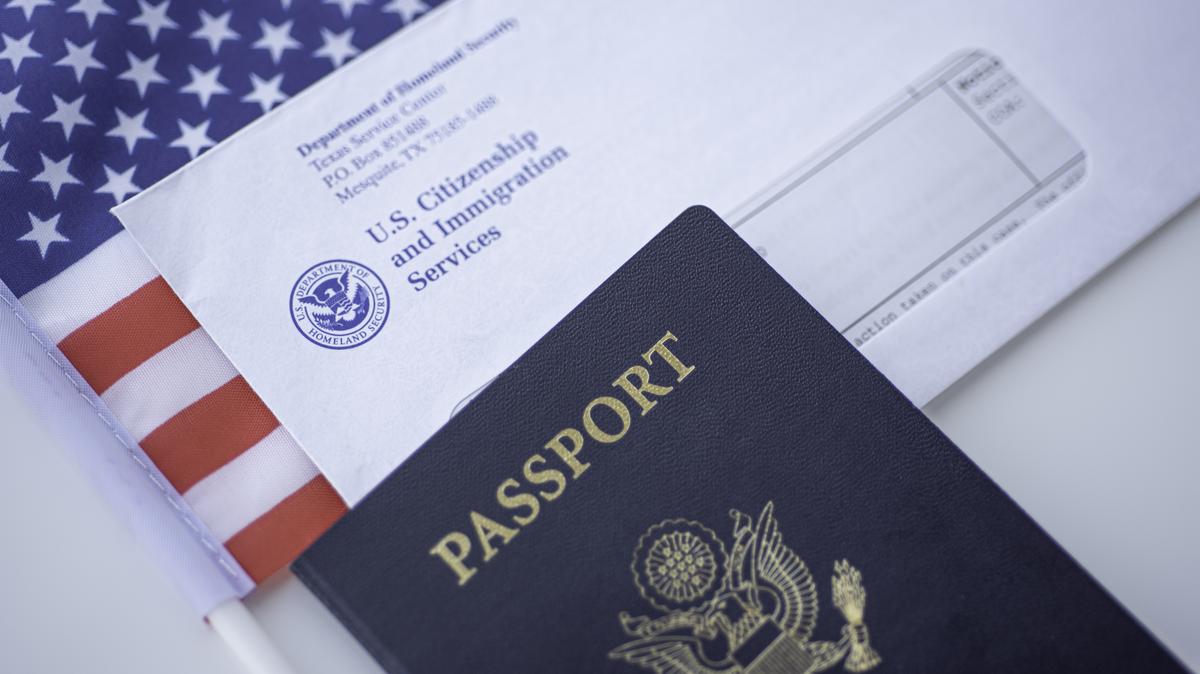 Passport of USA next to the Blurred Letter from USCIS and American flag.. Passport of USA next to the Blurred Letter from USCIS and American flag. Close up view.