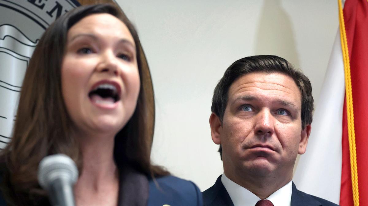 Florida Governor Ron DeSantis listens to Florida Attorney General Ashley Moody during a press conference in Orlando on Aug. 26, 2021.