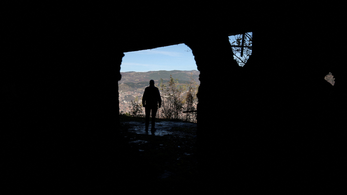 FILE PHOTO: A Bosnian worker looks out at Sarajevo through a hole in a war-damaged building that once marked the front line during the 1992–95 Bosnian War, in Sarajevo, Bosnia and Herzegovina, November 13, 2025. REUTERS/Amel Emric/File Photo
