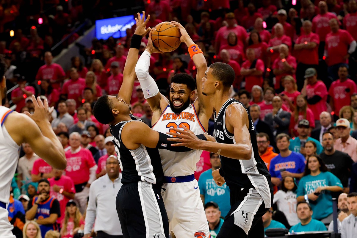  Jun 3, 2026; San Antonio, Texas, USA; New York Knicks center Karl-Anthony Towns (32) controls the ball between San Antonio Spurs forward Keldon Johnson (3) and forward Victor Wembanyama (1) during the first quarter during game one of the 2026 NBA Finals at Frost Bank Center. Mandatory Credit: Geoff Burke-Imagn Images 