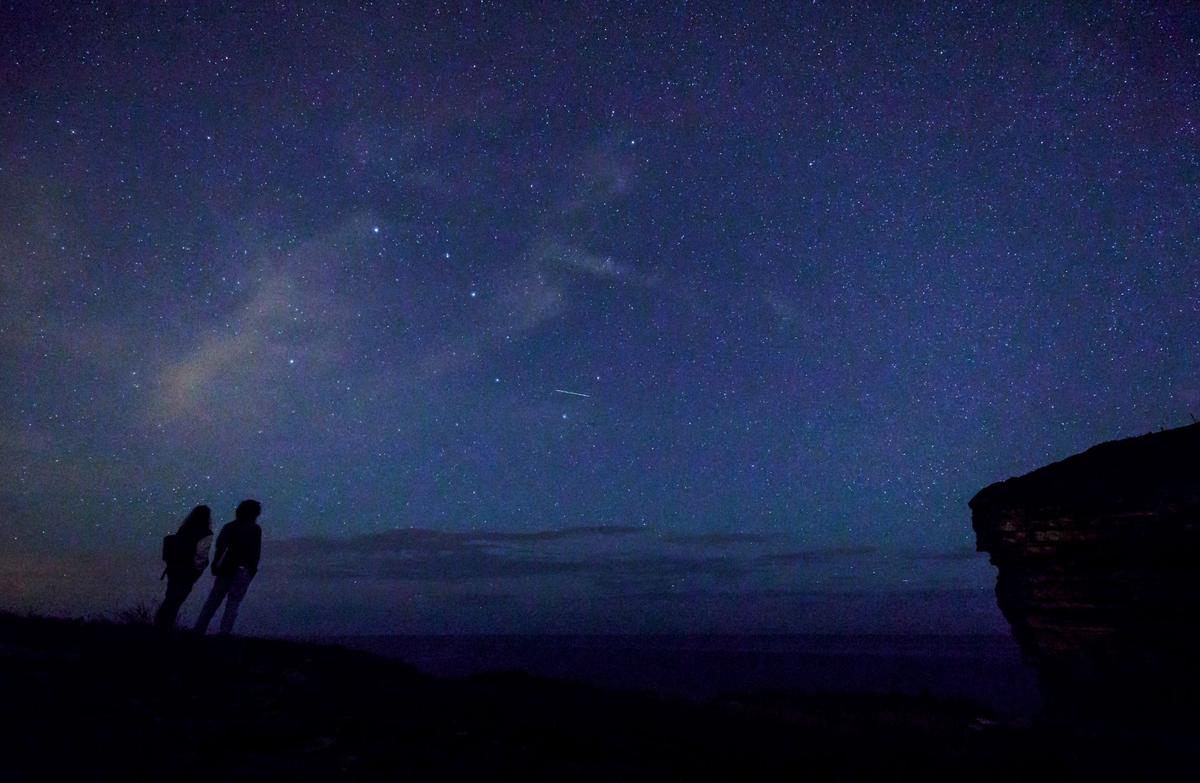 This picture taken on August 12, 2017, shows a couple enjoying Perseid meteor along the Milky Way illuminating the dark sky near the Comillas, Cantabria community in northern Spain uring the Perseid meteor shower. The Perseids will reach their peak on Tuesday, Aug. 12, and Wednesday, Aug. 13, 2025. 
