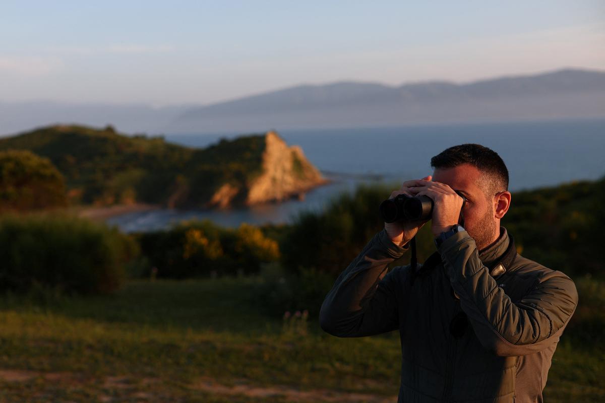 Ecologist Joni Vorpsi uses his binoculars at the Vjosa-Narte protected area where a luxury resort is planned by a company linked with Donald Trump's son-in-law Jared Kushner, near Vlora, Albania, May 9, 2026. REUTERS/Florion Goga