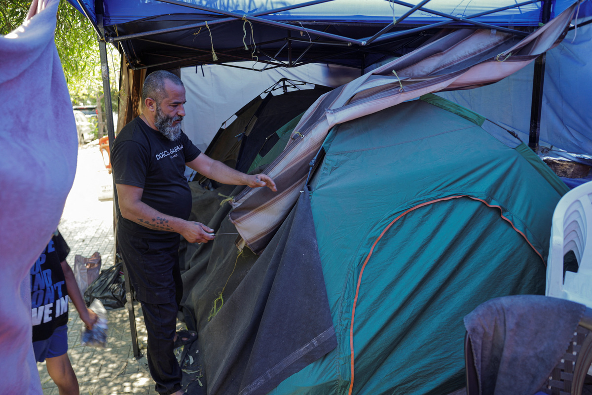 A man packs his belongings on a sidewalk in Beirut, where he and his family have been living in a tent, as he prepares to return home following an interim deal between the U.S. and Iran, in Beirut, Lebanon, June 24, 2026. REUTERS/Khalil Ashawi